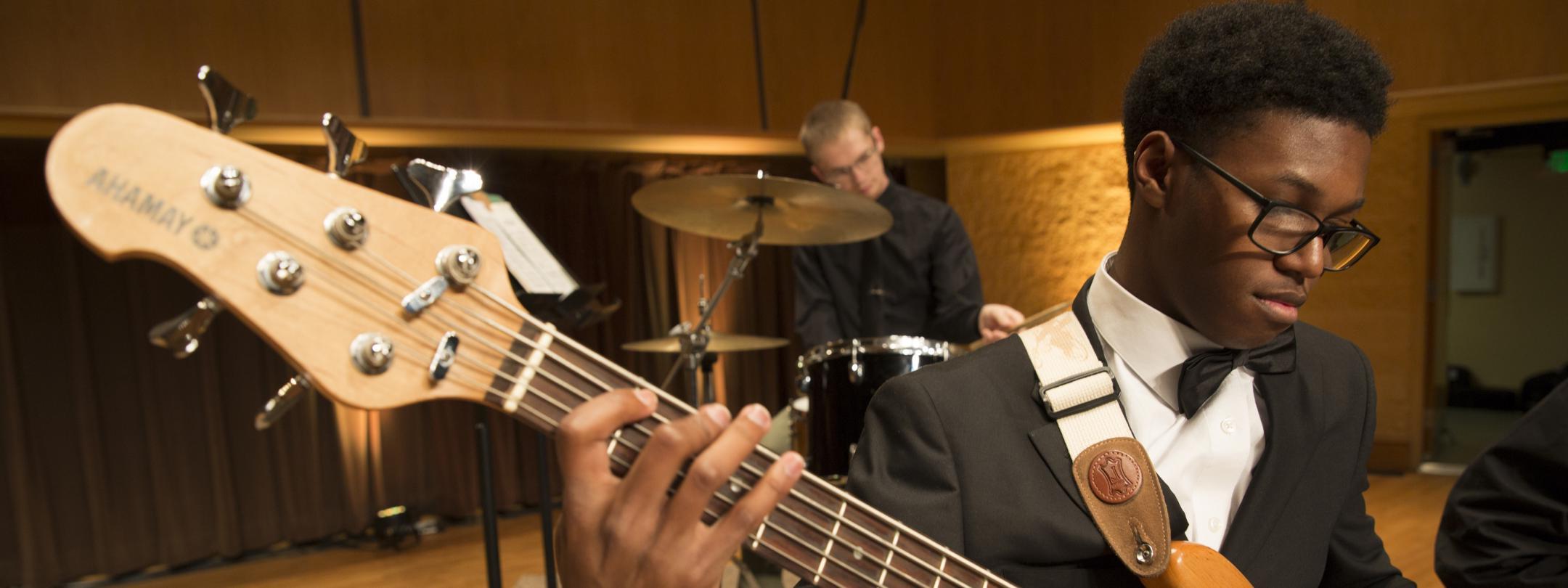 Student playing in a guitar in a concert.